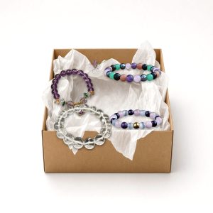 Four stretch bead bracelets in an open kraft gift box with white tissue paper